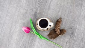 Coffee cup with wooden cones and tulip on wooden table background. *UHD.