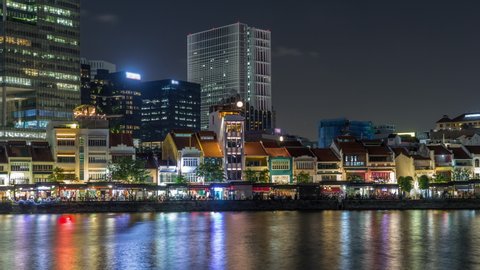 Singapore quay with mall restaurants and tall skyscrapers in the central business district on Boat Quay night timelapse hyperlapse. Houses reflected in water
