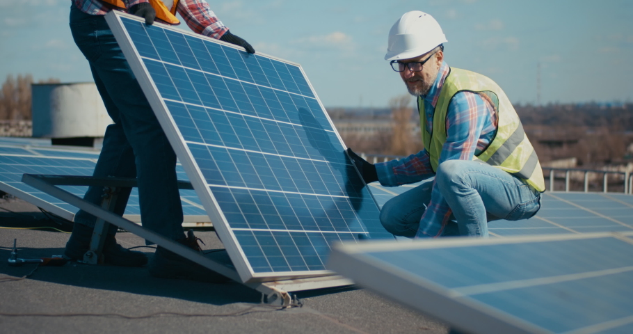 Medium shot of technicians installing solar panels on metal stand | Shutterstock HD Video #1048972282