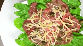 Carpaccio with arugula leaves, capers and grated cheese