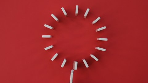 Domino Effect. Dominoes falling in slow motion video on red background. Circle of dominoes. Coronavirus pandemic concept
