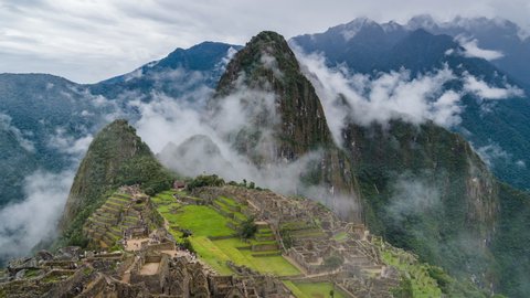 Zoom out time lapse view of mysterious Machu Picchu Inca ruins shrouded in mist high in the Andes mountain range, Cusco Region, Peru.