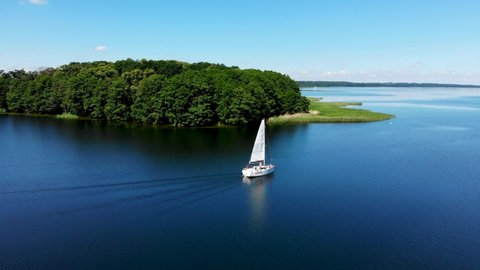 Aerial view of sailboat on the beautiful lake Kisajno on a sunny day. Mazury by drone, Poland