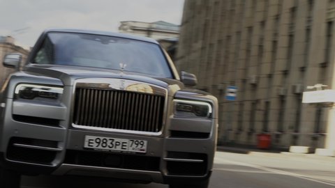 Moscow, Russia - 13 03 2020: Rolls Royce Cullinan is moving down the street. The driver is carrying a businessman. Expensive status car drives through intersection and turns right. Close up footage.