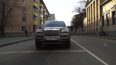 Moscow, Russia - 13 03 2020: Rolls Royce Cullinan is moving down the street. The driver is carrying a businessman. Expensive status car drives through intersection and turns left.