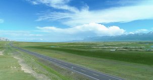 Aerial view of one car driving on the road in the broad plain under blue sunny sky at Xinjiang China drone landscape of grassland road trip