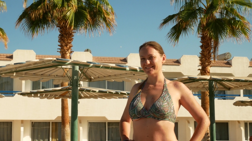 Pretty woman in bikini sunbathe in sun at palm trees background. Summer vacation or enjoying suntan concept