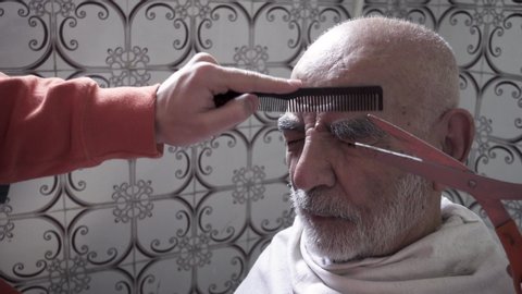 Close-up Shot of a 80 years old Elderly Turkish Muslim Man Having His Eyebrows Trimmed