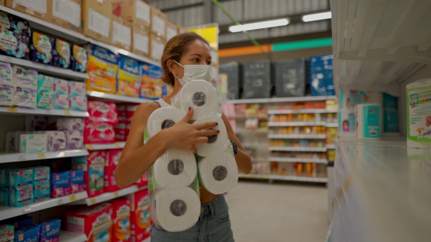 young woman wearing protect mask takes pack of toilet paper in shop with empty shelves Royalty-Free Stock Footage #1049017906