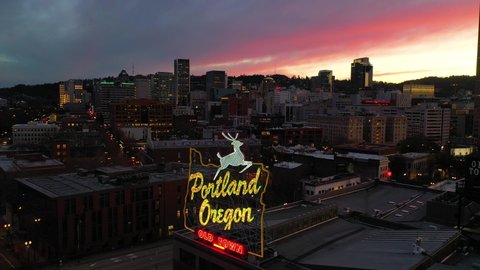 CIRCA 2010s - Moody aerial around Portland Oregon stag deer sign and downtown old town cityscape and business district at sunset or dusk.
