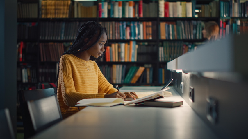 University Library: Gifted Black Girl uses Laptop, Writes Notes for the Paper, Essay, Study for Class Assignment. Students Learning, Studying for Exams College. Side View Portrait with Bookshelves | Shutterstock HD Video #1049020681