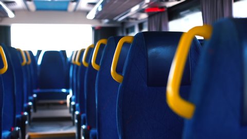 Transmission of coronavirus COVID 19 in public transport. Yellow handrails in an empty moving bus during quarantine. Blue color of seats, perspective. Public transport.