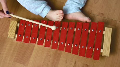 The child plays with sticks on the red xylophone, percussion instrument, top view