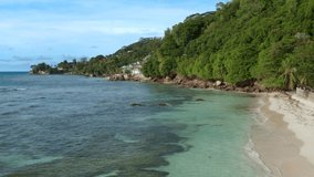 Backward flying drone video of tropical beach of Seychelles.