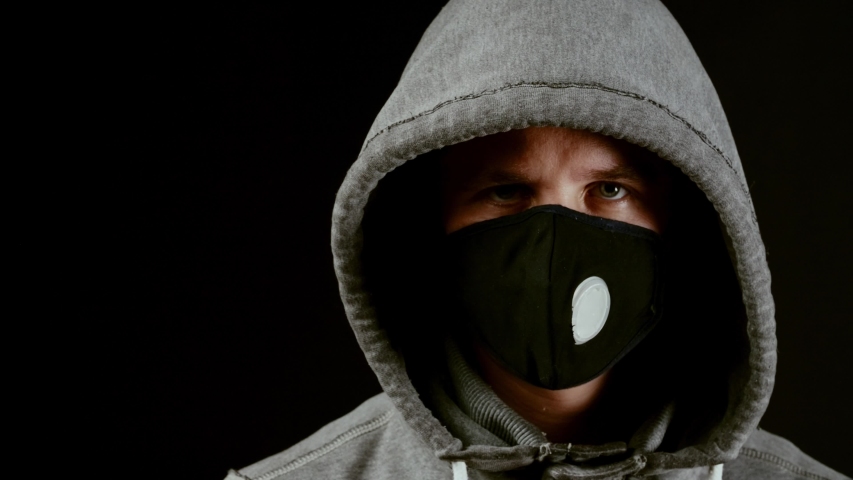 White male wearing face mask offers white protective mask to the viewer