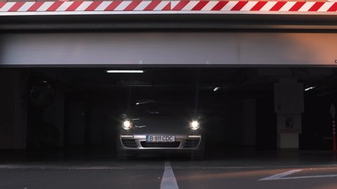 Bucharest, Romania- 10.10.2019: Handsome businessman driving a luxury Porsche 911 Carrera 4s while getting out of a garage. Concept of business, traveling, luxury