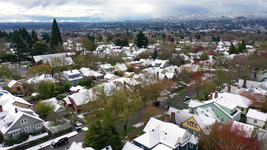 CIRCA 2010s - Aerial over snowy winter neighborhood, houses, suburbs in snow in Portland, Oregon.