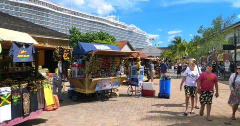 FALMOUTH, JAMAICA - SEPTEMBER 25, 2018: Tourists from "Harmony Of The Seas" Royal Caribbean cruise ship visit local shopping area with palm trees in Falmouth, Jamaica, 4K