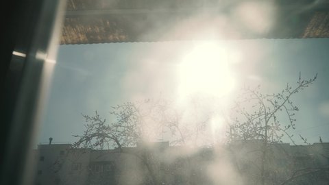 4K Sun shines through window under ceiling. Room, outside the windows street, sunny sky, trees, houses. Slow motion. 3840x2160