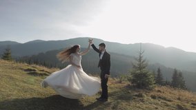 Newlyweds. Lovely young caucasian bride and groom dancing on mountain slope. Wedding couple. Happy family. Man and woman in love. Autumn. Bride in gorgeous wedding dress. Slow motion - Powered by Shutterstock - Get 15% off with code: PIKWIZARD15