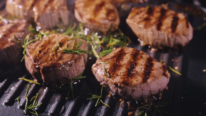 Delicious juicy meat steak cooking on grill. Aged prime rare roast grilling tenderloin fresh marble tenderness beef. Prime beef fry on electric roaster, rosemary, black pepper, salt. Slow motion. Royalty-Free Stock Footage #1049059702