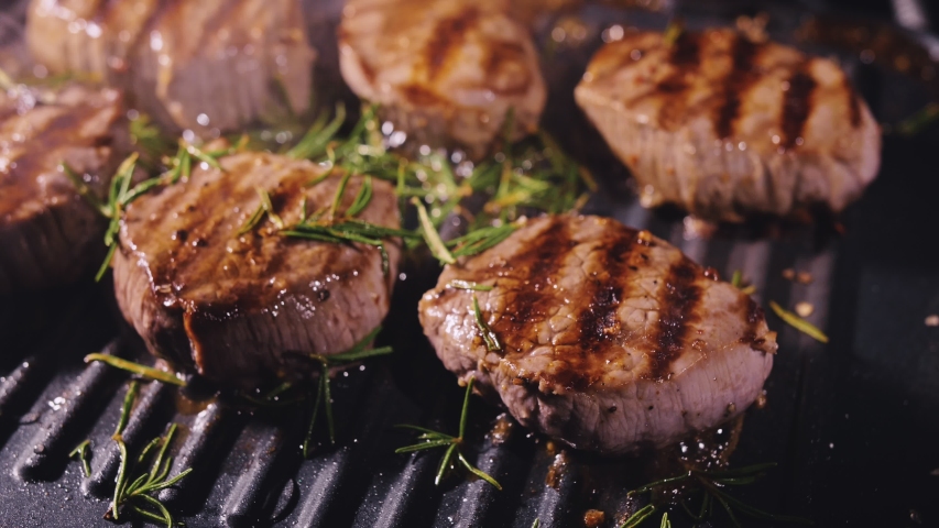 Delicious juicy meat steak cooking on grill. Aged prime rare roast grilling tenderloin fresh marble tenderness beef. Prime beef fry on electric roaster, rosemary, black pepper, salt. Slow motion. | Shutterstock HD Video #1049059702