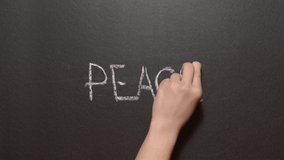 Peace. A left female hand writes the word "peace" by pink chalk on a black board. Conceptual chalk drawing - Powered by Shutterstock - Get 15% off with code: PIKWIZARD15