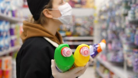 Woman Wearing Face Mask During Coronavirus Shopping And Stocking Up For Household Chemicals At Supermarket. 