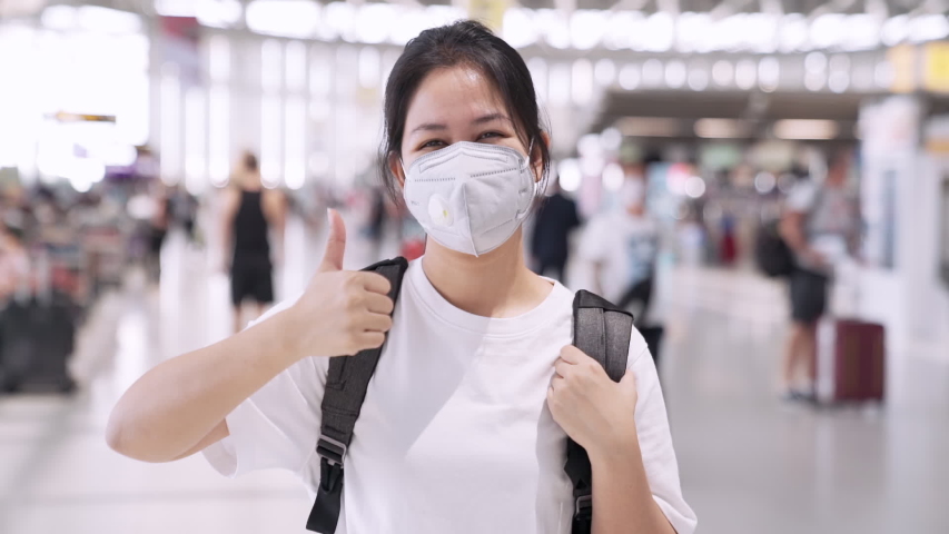 Asian woman wearing protective mask and show thumbs up at outdoor public airport terminal. Asia girl feeling safety. the concept health and safety, N1H1 Coronavirus 2019-nCov flu, virus protection. Royalty-Free Stock Footage #1049076934