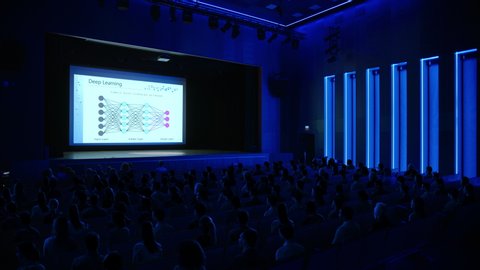 Crowd of Tech People in Cinema Theater Watching New High Tech Product Neural Network Machine Learning Software Presentation on Big Screen. Tech Business Conference Auditorium Hall full of People