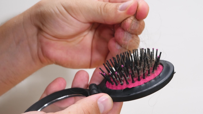 Messed hair after combing in hairbrush. Hairloss and weak health on white background. Concept of chemotherapy and cancer Royalty-Free Stock Footage #1049098072