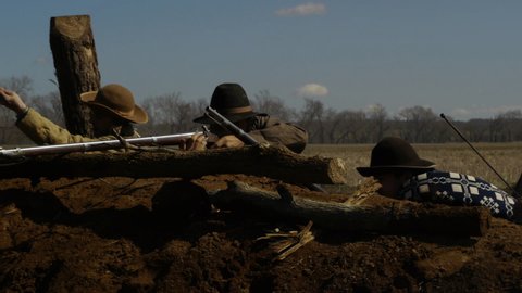 VIRGINIA - OCTOBER 2018 - Civil War Confederate Soldiers reenactment -- Re-enactors firing and loading musket rifles, gun with black powder and lead bullets in earthen trenches on battlefield.