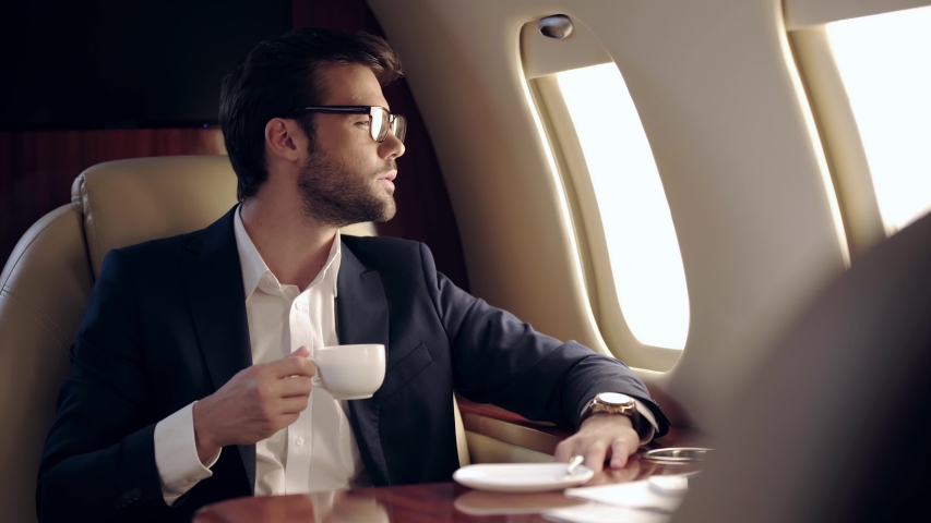 businessman holding coffee and looking in illuminator while traveling by plane Royalty-Free Stock Footage #1049107306