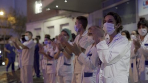 MADRID, SPAIN - MARCH 25 2020. Medical staff from the Fundacion Jimenez Diaz hospital who are fighting coronavirus applaud back the people of Madrid and police officers for their support