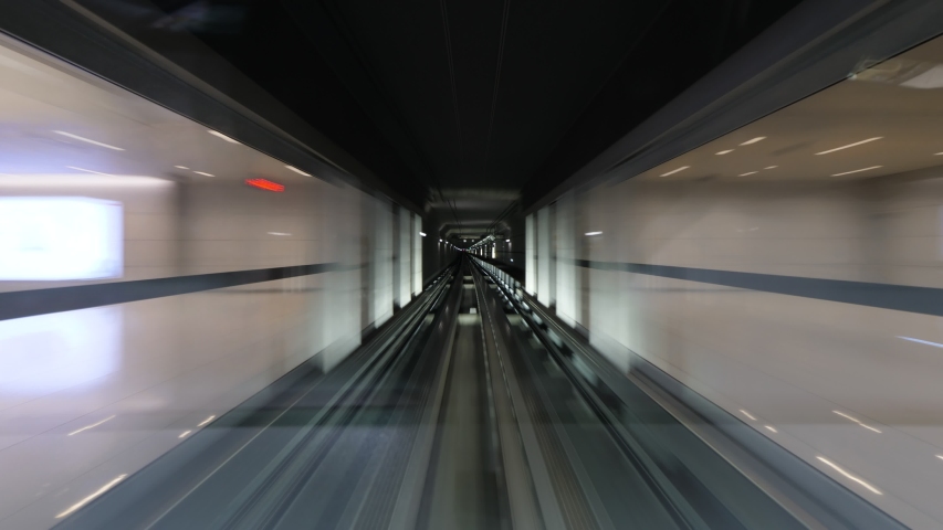 Automated people mover rush at tunnel, view through cabin windshield, driver window perspective. Time lapse shot, fast motion forward, dark walls seen in motion blur Royalty-Free Stock Footage #1049111875