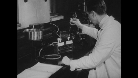 1950s: man in lab coat works with test tubes of pneumococci and smallpox virus, puts test tube in pan of water over Bunsen burner, looks at pocket watch, writes in notebook