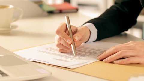 Close up of executive hands checking and signing contract on a desk at office