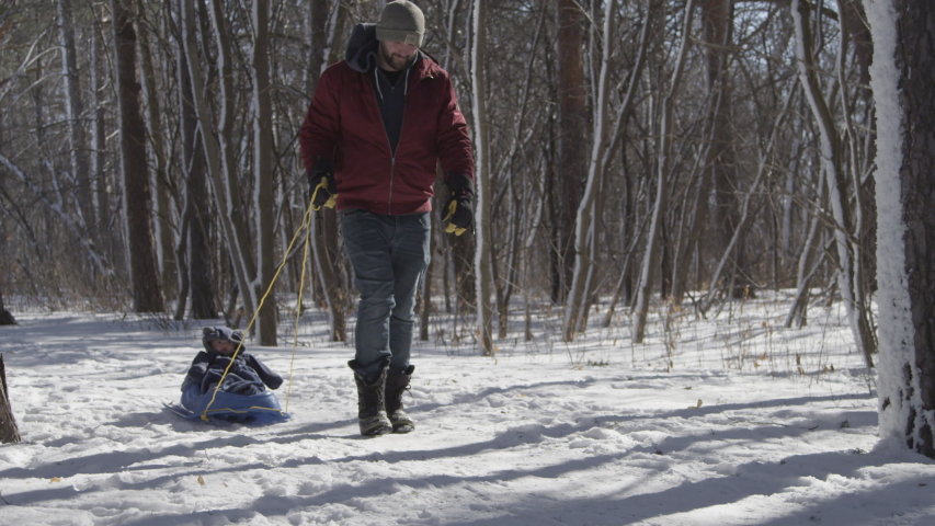 A man slips and falls while walking with his infant son in a sled Royalty-Free Stock Footage #1049118337