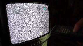 Old vintage remote control and noise interference on TV screen, man changing channels and surfing broadcast. Retro electronics, 70s TV transmissions