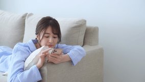 Young asian woman using a smart phone in the living room.