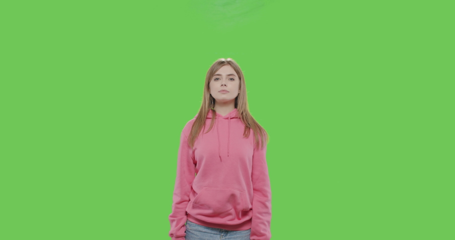 Young woman shooting gesture on green screen.Tired girl making sign gun by hand posing at chroma key background. Smoke coming out of head. 4k video footage slow motion