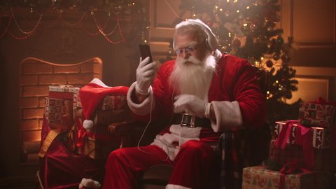 Dancing Santa Claus with headphones and a mobile phone in his hands. Listen to music online. Jerky and dynamic songs