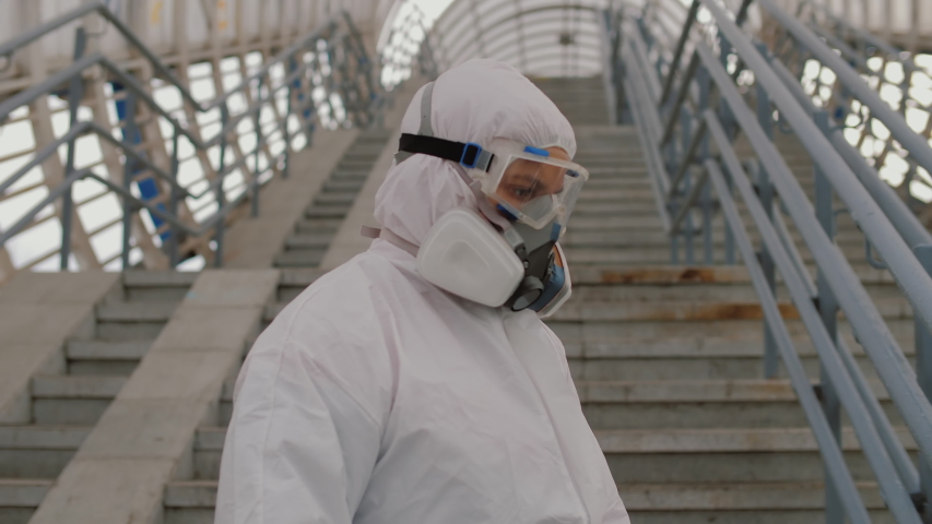 Virologist in protective suit disinfects surface, sprays liquid chemicals on handrails. Sanitary measures against coronavirus in public place Covid-19 coronavirus spreading prevention