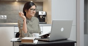 Business woman talking on video communication using headphones and laptop and making notes in a notebook. Online training or distance work.