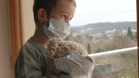 young boy, kid, child with protective mask with teddy bead, home quarantine