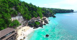 Top view of Uluwatu cliffs and beach. Aerial video. Beautiful waves rolling over rocky beach, shot in Bali, Indonesia