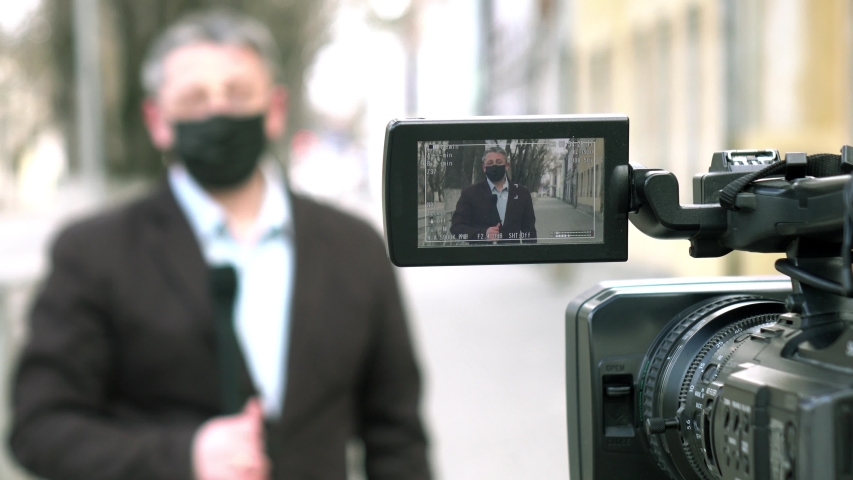 A middle- aged European journalist in a protective medical mask is reporting in a deserted city. Concept of protection against dangerous coronavirus. Royalty-Free Stock Footage #1049181841
