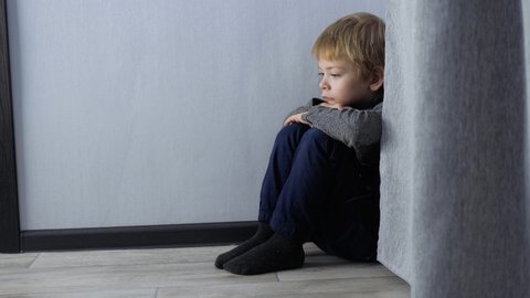 sad upset boy sitting in the corner. Child punished sitting crying lifestyle in the corner. Domestic violence concept. Child abuse