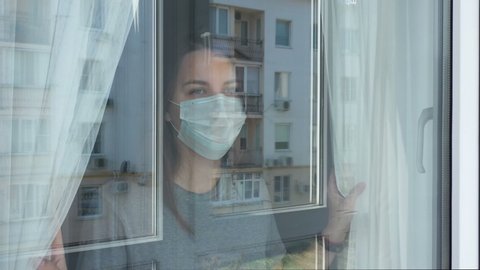 Woman in Quarantine Looking out the Window. Staying Home in Self-Quarantine