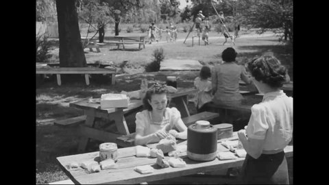 CIRCA 1940s - Children play outdoor games, enjoy a playground, and eat picnic lunch a birthday party in a park.